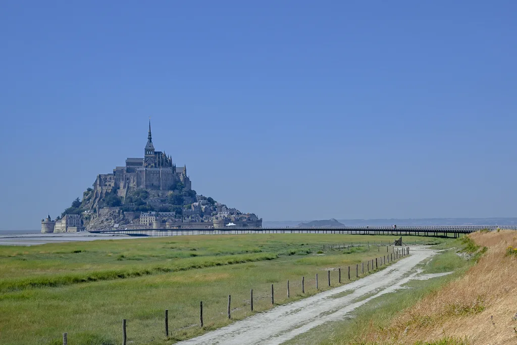 Le Mont-Saint-Michel apparaît au bout du chemin de la digue et de sa passerelle