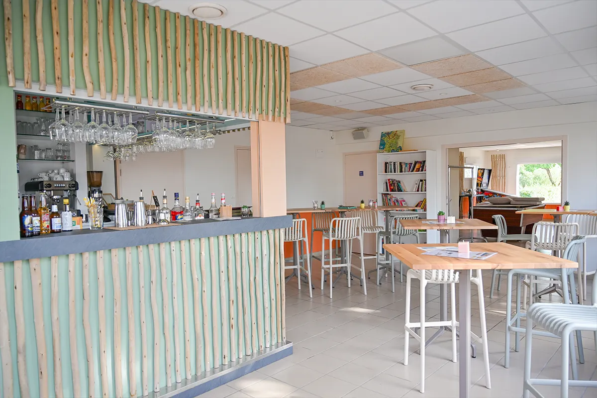 bar salle commune mobilier bois Comptoir du bar en bois clair et salle commune du camping avec tables et chaises