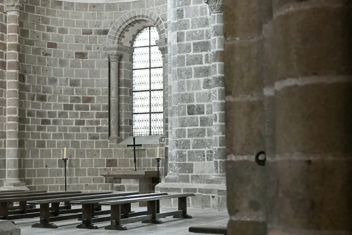 chapelle romane abside abbaye Abside romane de l'abbaye avec fenêtre en ogive, croix et bougies allumées