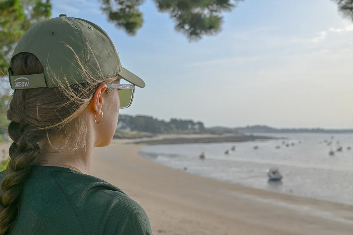 femme vue plage damgan Jeune femme en casquette regardant la plage et la mer à Damgan, vue de dos
