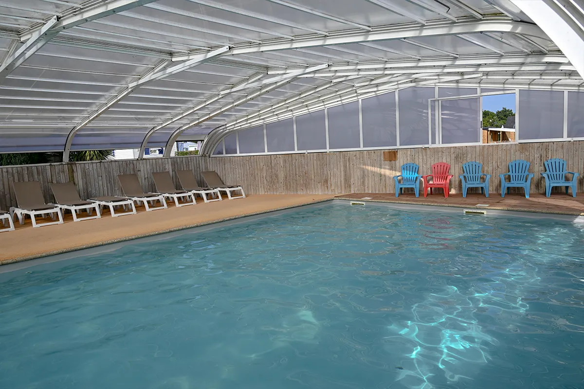 piscine couverte chaises colorees bassin Grand bassin de piscine couverte avec chaises bleues et rouges alignées le long du mur