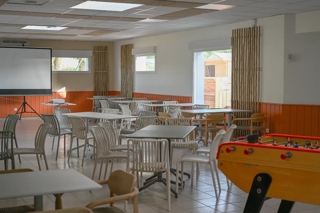 salle commune baby foot tables Salle commune du camping avec tables, chaises, écran de projection et baby-foot