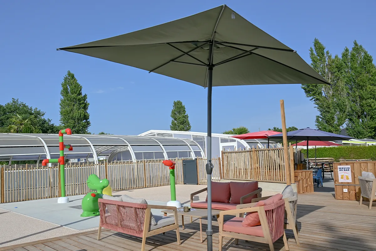 terrasse parasol vert jeux eau Grand parasol vert au-dessus des canapés de la terrasse avec les jeux d'eau en arrière-plan
