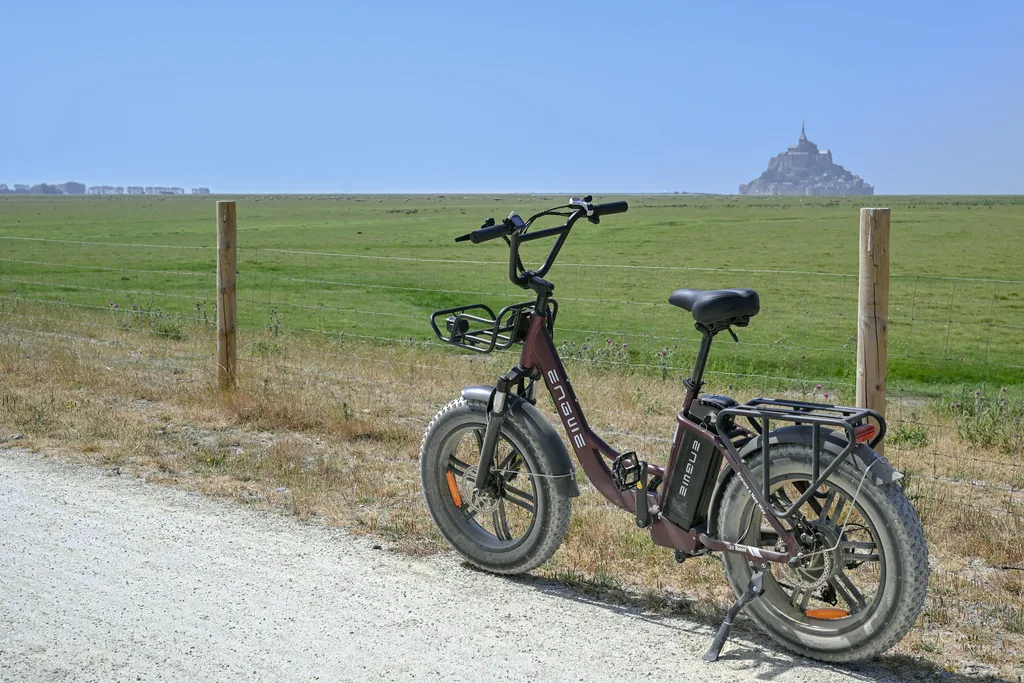 Vélo à assistance électrique garé le long d'un chemin avec le Mont-Saint-Michel au loin