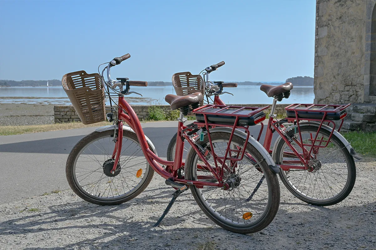 velos location ile aux moines Deux vélos de location avec paniers garés au bord de la mer, île aux Moines