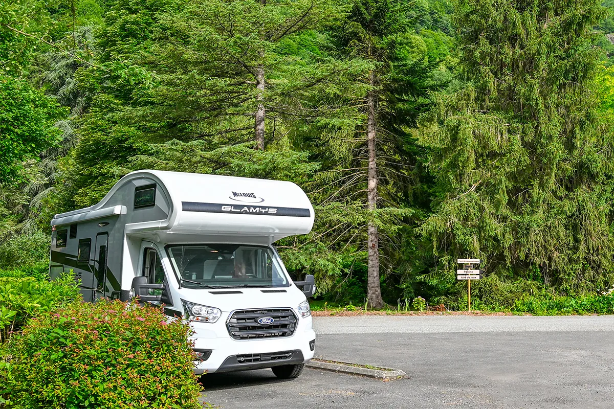 aire cc Camping-car sur l’aire de services du camping Pradelongue entourée de sapins